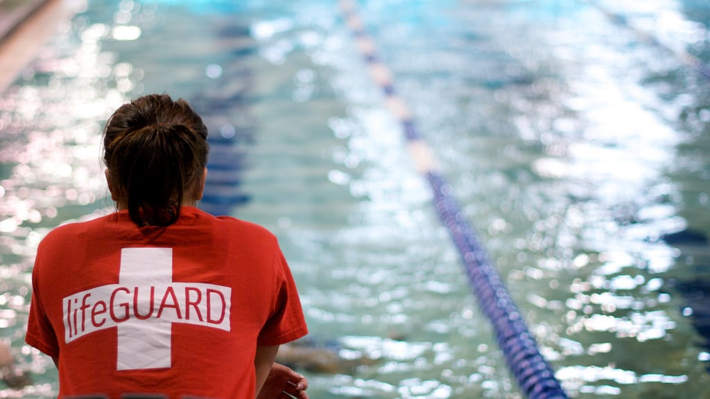 a lifeguard sits next to the pool