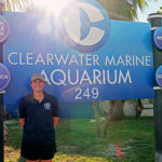 Photo of happy student scholarship recipient in front of the Clearwater Marine Aquarium sign